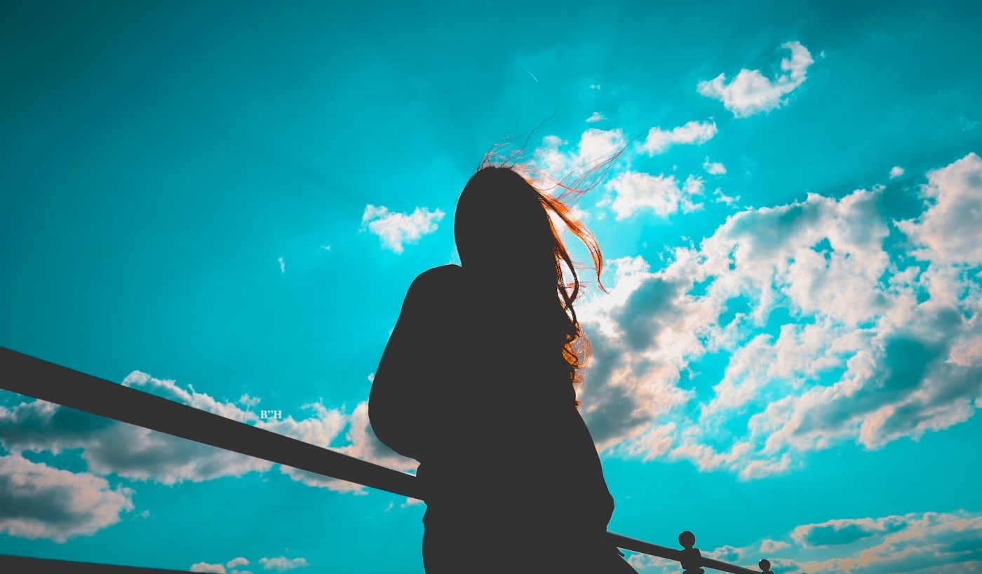 lonely woman grieving alone looking at sky and clouds