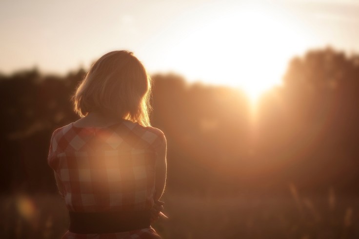back of woman thinking at sunset