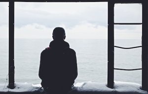 man sitting alone, holding in grief