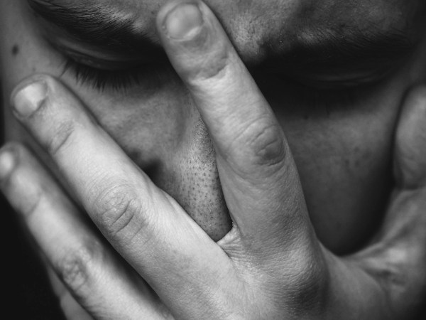 man holding his hand over his face in grief