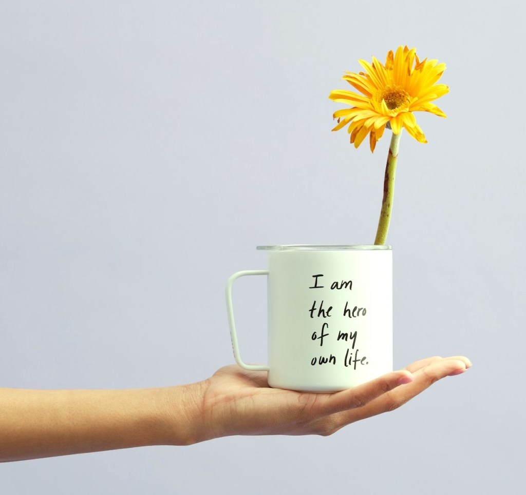 hand holding a cup with a flower for positivity