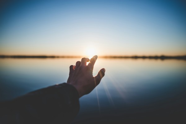 hand reaching out to sunrise hope