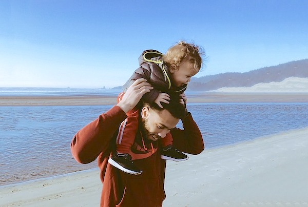 man holding small child on shoulders on beach, child loss at any age man holding small child on shoulders on beach, child loss at any age